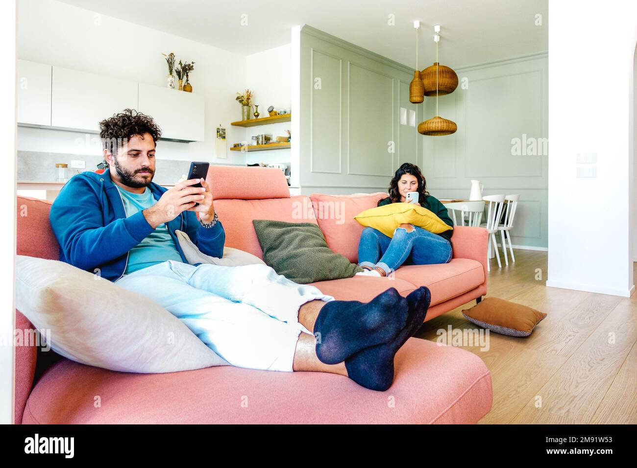 Pareja aburrida en el momento de desinterés ignorándose el uno al otro usando el teléfono celular móvil en casa - concepto de tristeza de apatía con el hombre y la mujer adictos Foto de stock