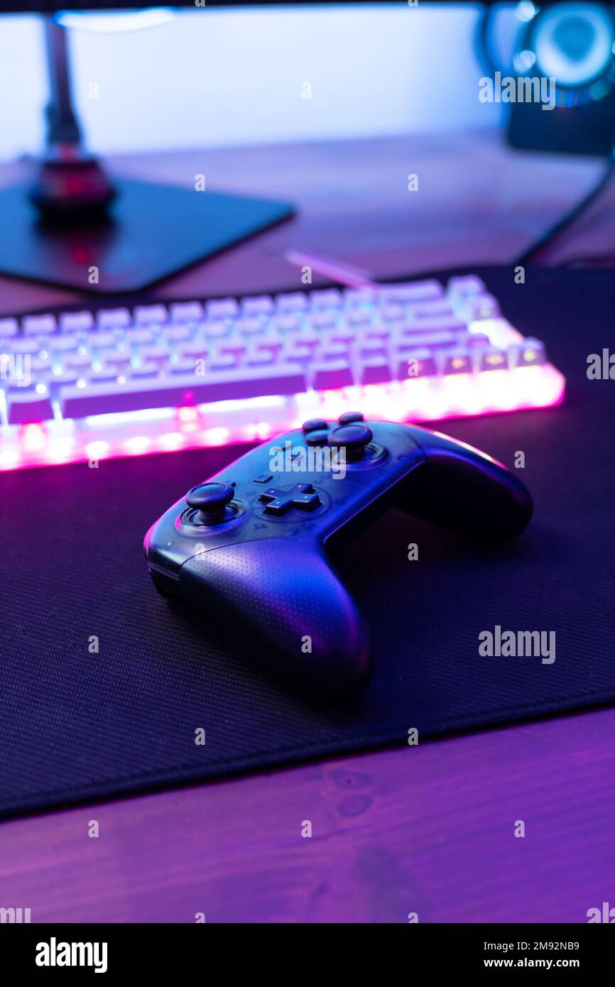 Alto ángulo de joystick inalámbrico negro colocado cerca del teclado  luminoso de la computadora en la mesa Fotografía de stock - Alamy