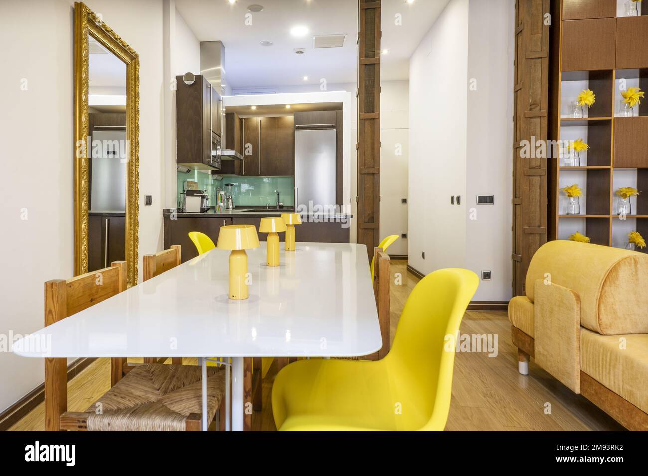Sala de estar de un apartamento de vacaciones tipo loft con columnas de  metal y muebles de diseño moderno con acentos amarillos y ocres y una mesa  de comedor blanca Fotografía de