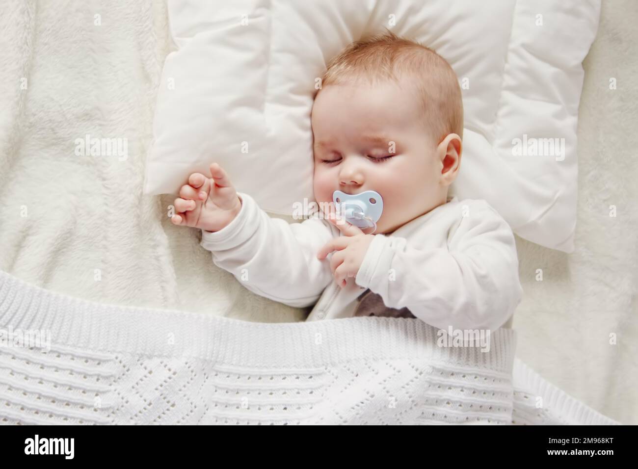 El bebé de cinco meses está acostado sobre una manta ligera en el  dormitorio vista superior de un niño encantador
