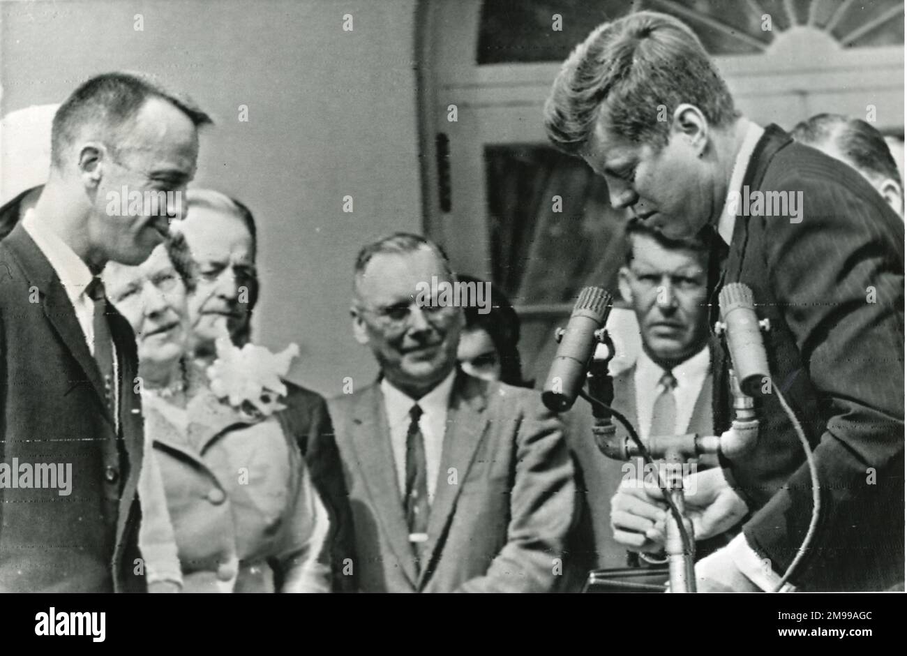 El presidente John F. Kennedy le ha devuelto una Medalla del Servicio Nacional de Aeronáutica y Administración Espacial, la cual dejó caer mientras presentaba el premio al comandante Alan Shepard Jr., a la izquierda, en una ceremonia en el Jardín de las Rosas de la Casa Blanca en Washington DC el 8 de mayo de 1961. Foto de stock