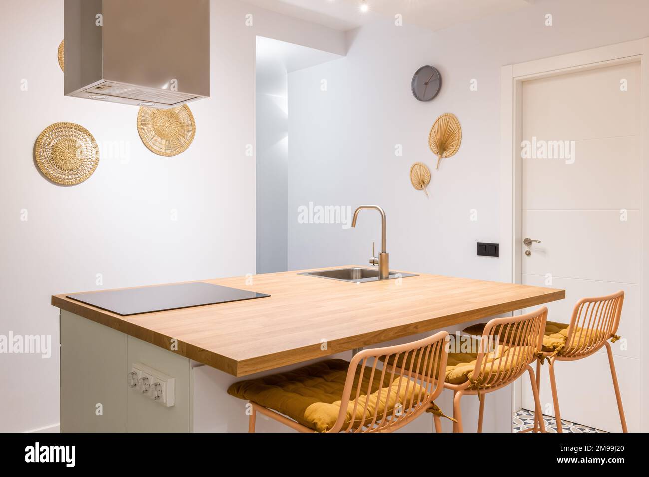 Mesa de madera y sillas altas en el centro de la luminosa cocina cálida de  moderno apartamento con electrodomésticos Fotografía de stock - Alamy