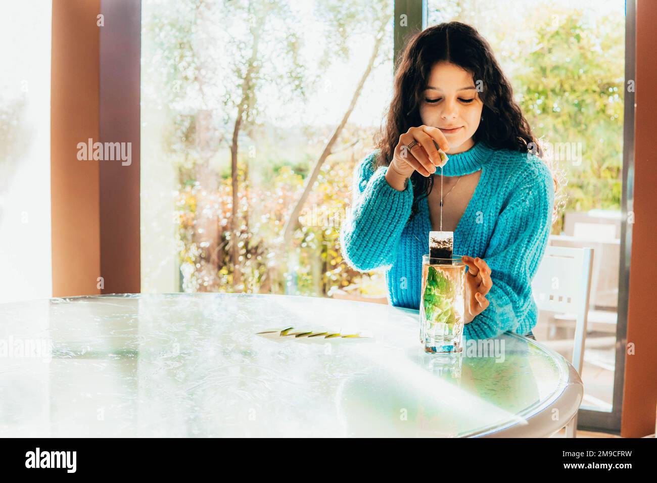 mujer soltera que prepara un té en la cocina contra el bambú Foto de stock