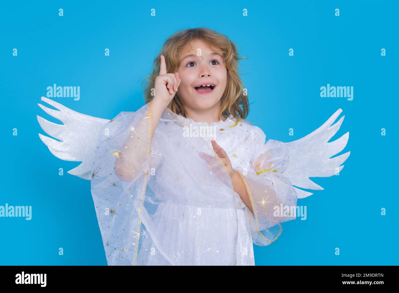 Ángel niño apuntando hacia arriba, gesto de punto. Día de San Valentín. Pequeño cupido ángel niño con alas. Retrato de estudio del niño angelical. Foto de stock