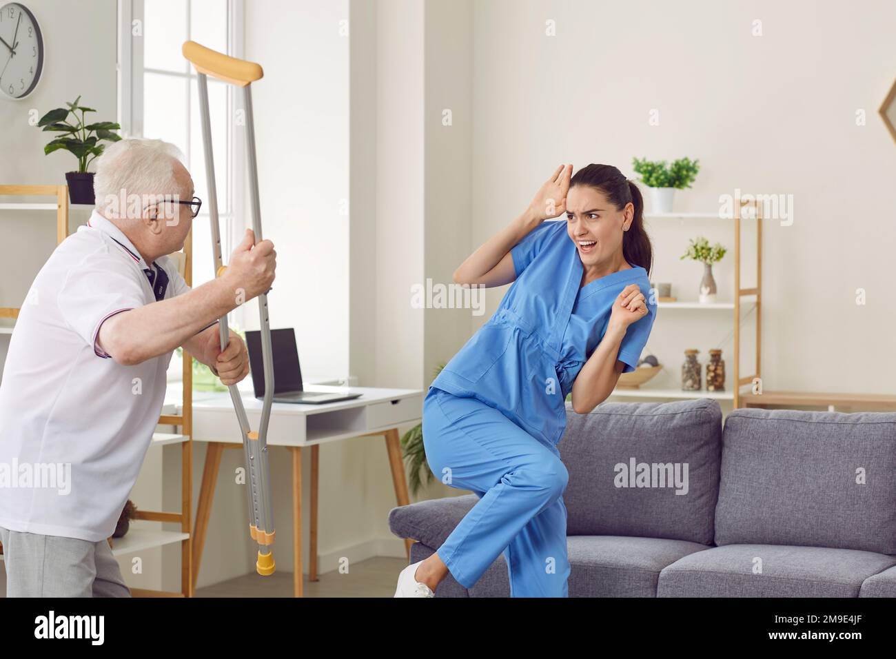 Hombre anciano agresivo enojado amenazando a su mujer cuidadora Foto de stock