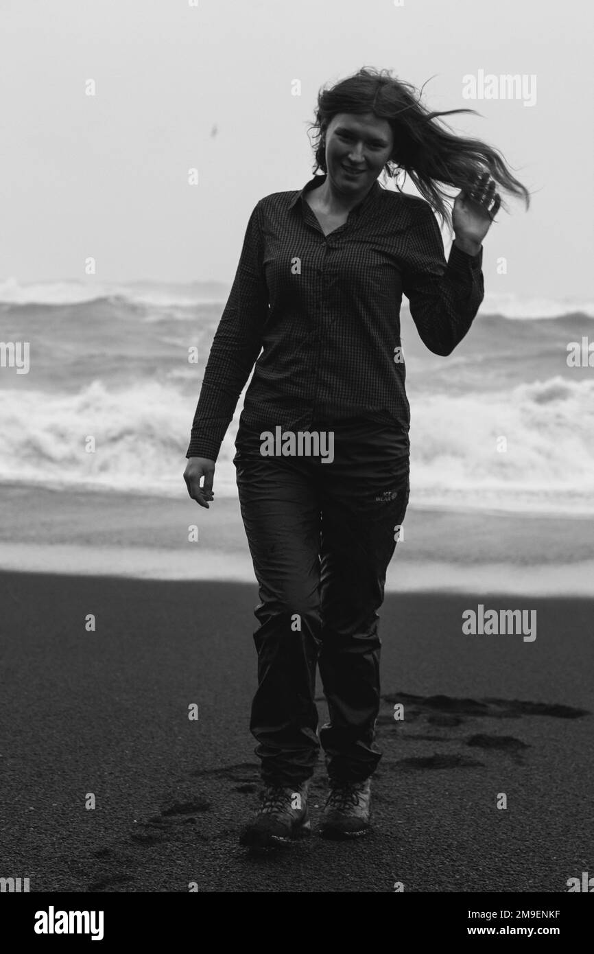 Turista en la playa negra en el viento fuerte monocromo fotografía escénica Foto de stock