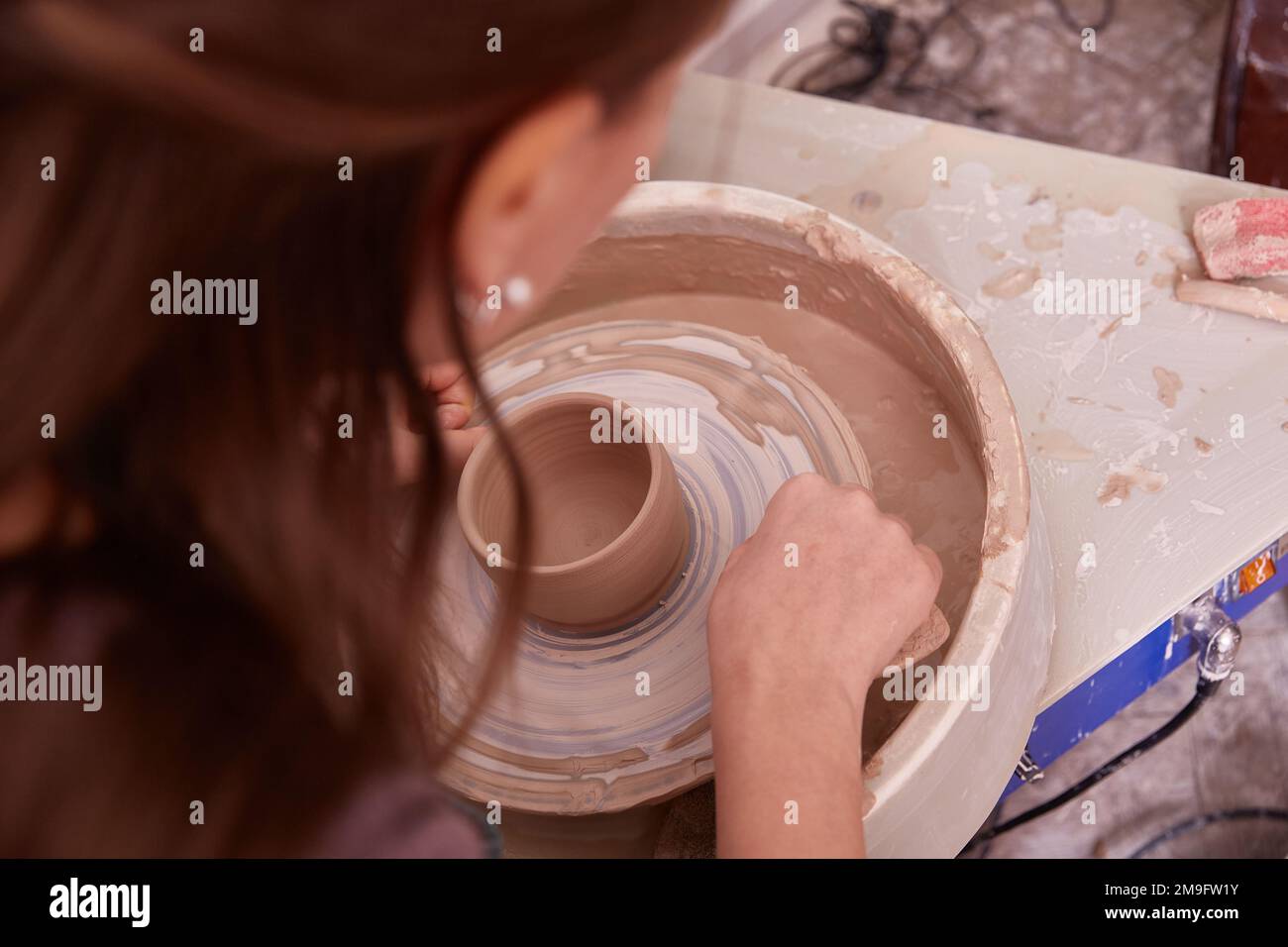 las manos de un ceramista hacen platos en la rueda de un alfarero Foto de stock