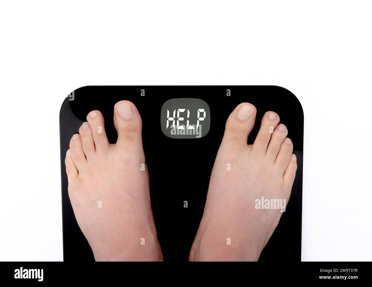 Una persona de pie en una escala y mostrando la palabra AYUDA en la pantalla de una escala digital. Concepto: Pérdida de peso Foto de stock