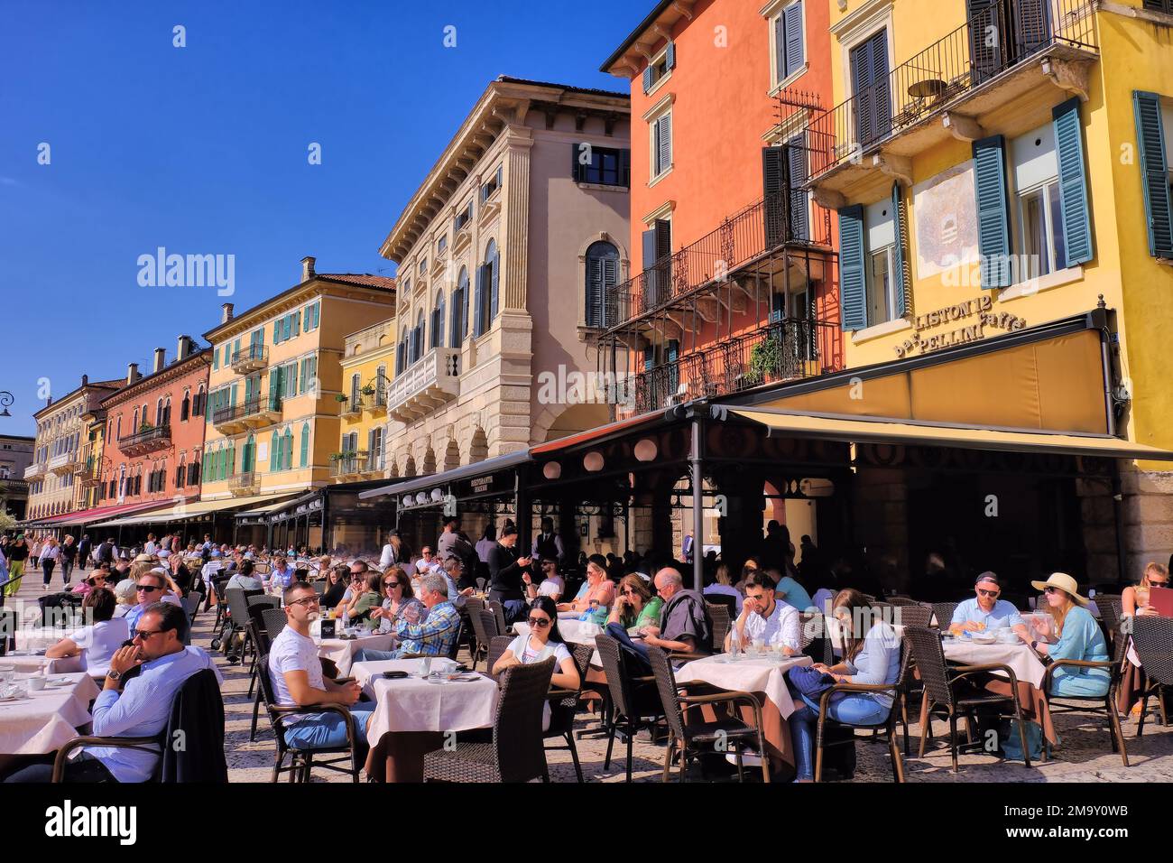 Verona: Edificios coloridos con gente comiendo en restaurantes en Piazza Bra, Verona, Veneto, Italia Foto de stock