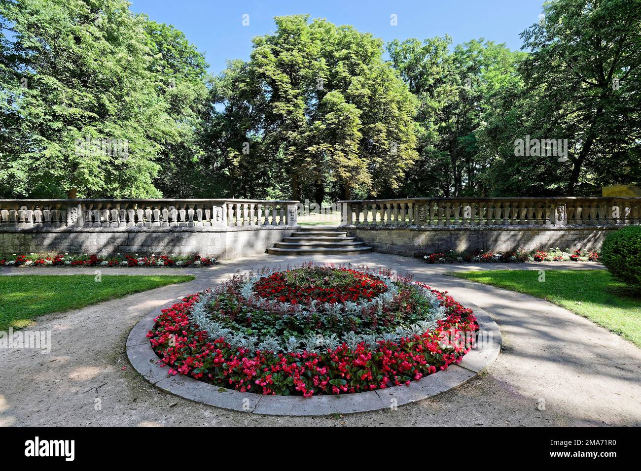 Cama redonda con flores, detrás de ballustrade con escaleras, árboles viejos altos, parque del castillo, residencia Ellingen, construido 1708-1760, castillo, Orden Teutónica Foto de stock