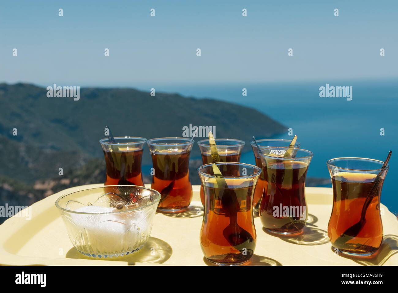 Dos vasos de cristal de té negro con platillos en la bandeja azul al aire libre en el jardín. Escena soleada todavía vida en silla de madera. Té azerbaiyano tradicional Foto de stock