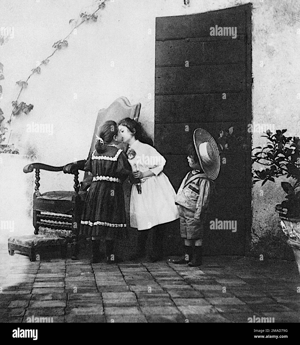 Giuseppe Primoli - El beso - 1890-1895 Dos chicas jóvenes intercambian un beso con un niño pequeño en la atención rapt. Foto de stock