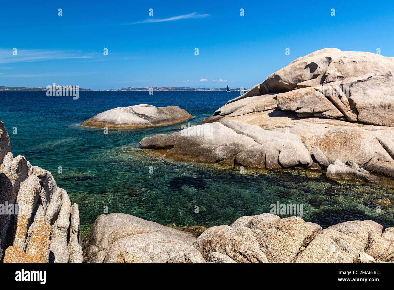 Rocas erosionadas y vistas del Golfo di Arzachena desde Spiaggia Tre Monti con el mar Mediterráneo claro, Cairn y la lejana Tanca Manna, Cerdeña, Italia Foto de stock