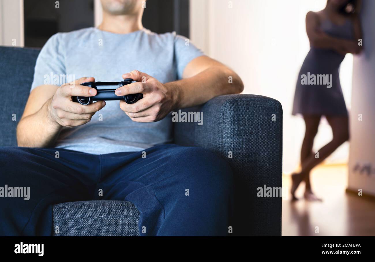 Pareja que tiene problemas con los videojuegos. Novia celosa de la tecnología. Matrimonio distante, divorcio. Esposa solitaria infeliz, esposo perezoso ignorando a la familia. Foto de stock