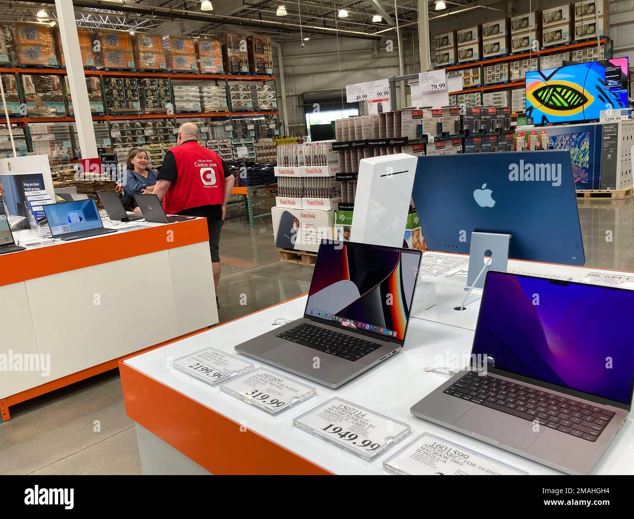 A sales associate helps a prospective customer as laptops sit on