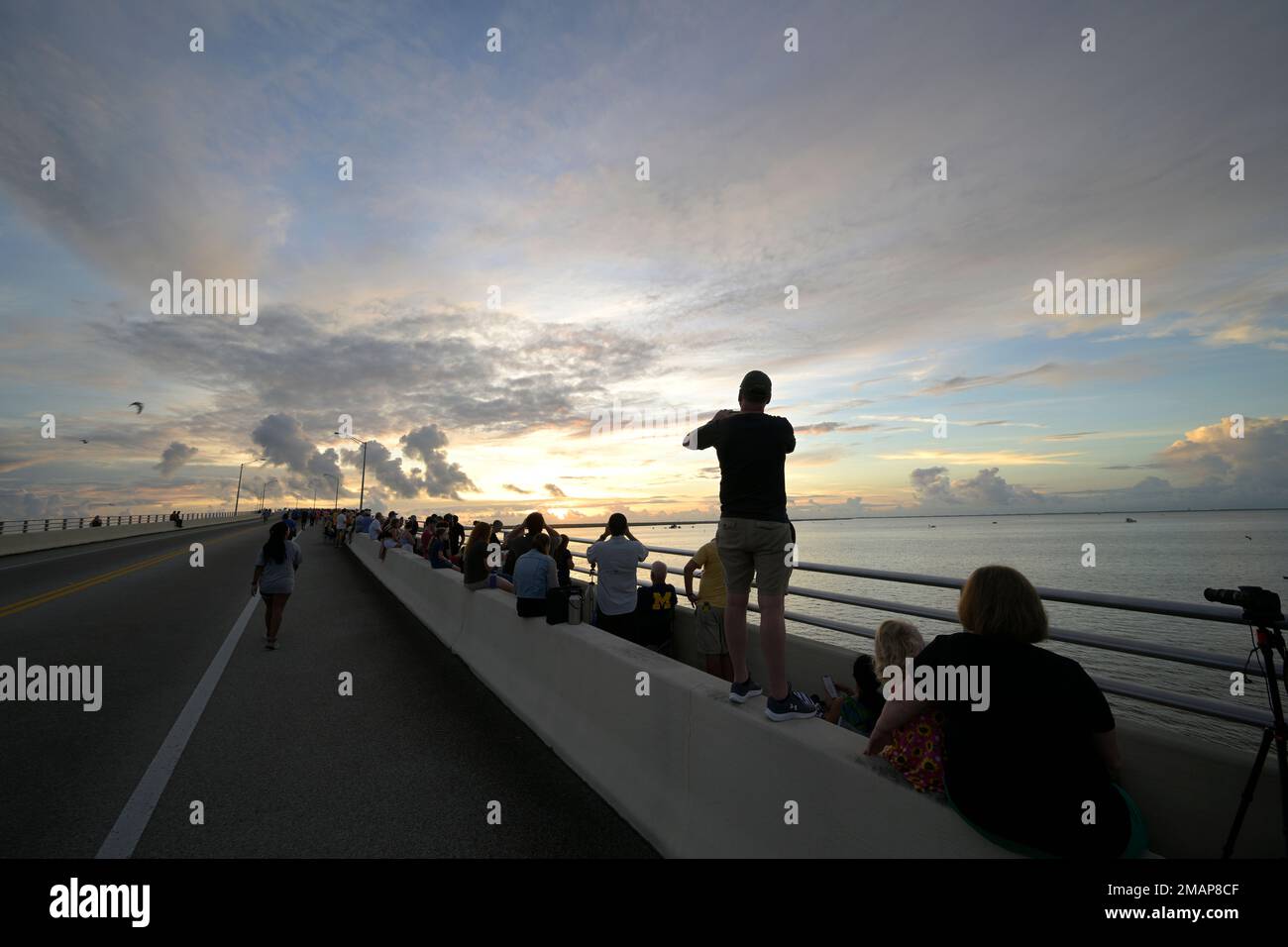 Spectators watch a sunrise from the Max Brewer Bridge while waiting to view  the launch on Pad 39B for the Artemis I mission to orbit the moon at the  Kennedy Space Center