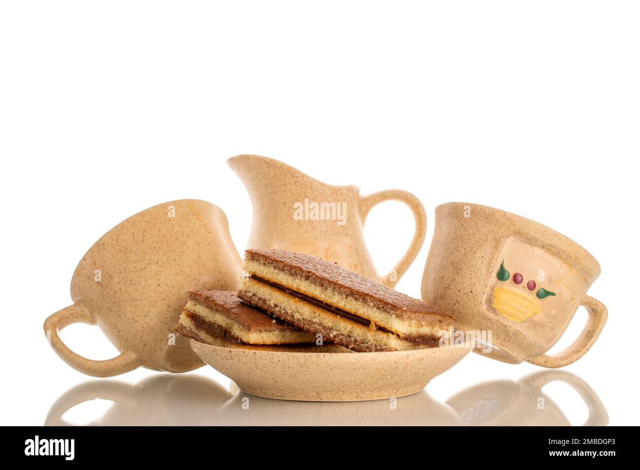 Dos mini bizcocho de cacao en platillo de cerámica con dos tazas y jarra de  leche, macro aislado sobre fondo blanco Fotografía de stock - Alamy