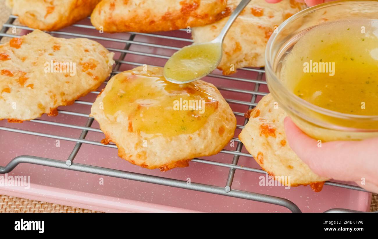 Aderezo de galletas con una mezcla de mantequilla derretida y condimento de ajo. Receta de galletas de queso recién horneadas Foto de stock