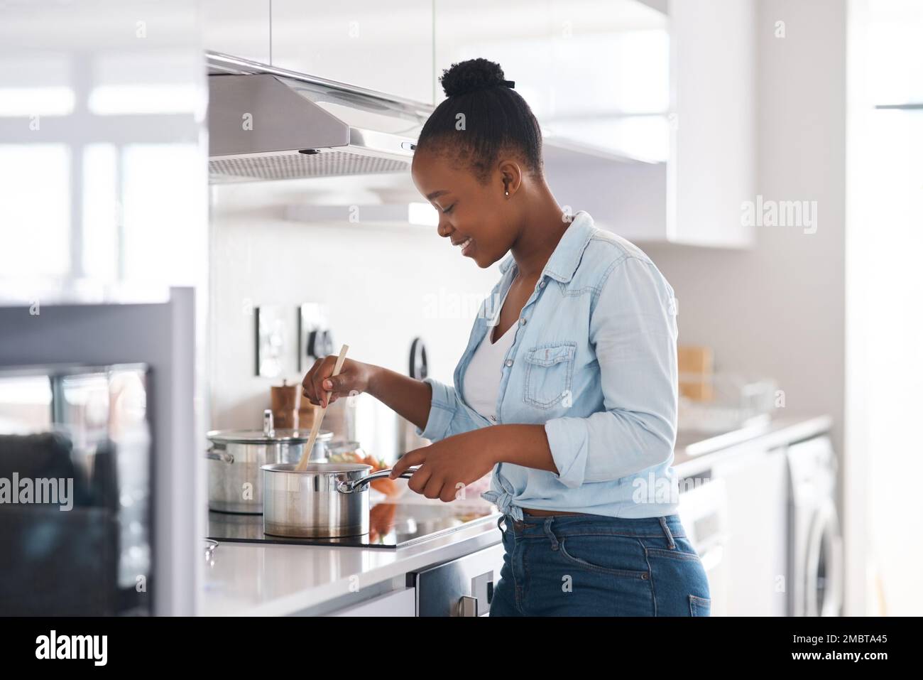 Mujer cocinando en la cocina en una placa de inducción con extractor de  olores