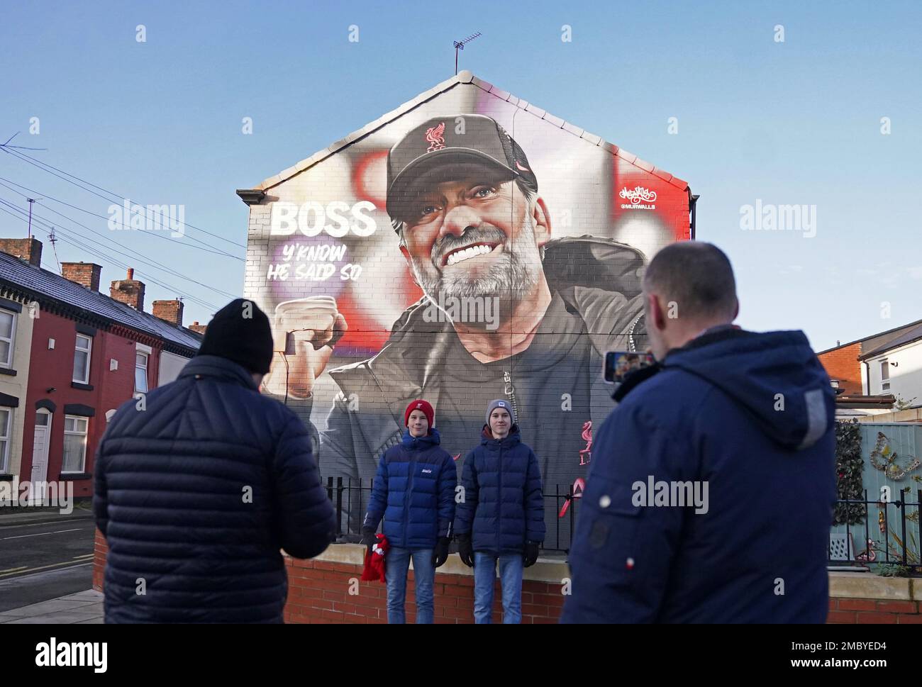 Los aficionados posan para una foto junto a un mural del entrenador del Liverpool Jurgen Klopp en una casa cerca del suelo antes del partido de la Premier League en Anfield, Liverpool. Fecha de la foto: Sábado 21 de enero de 2023. Foto de stock