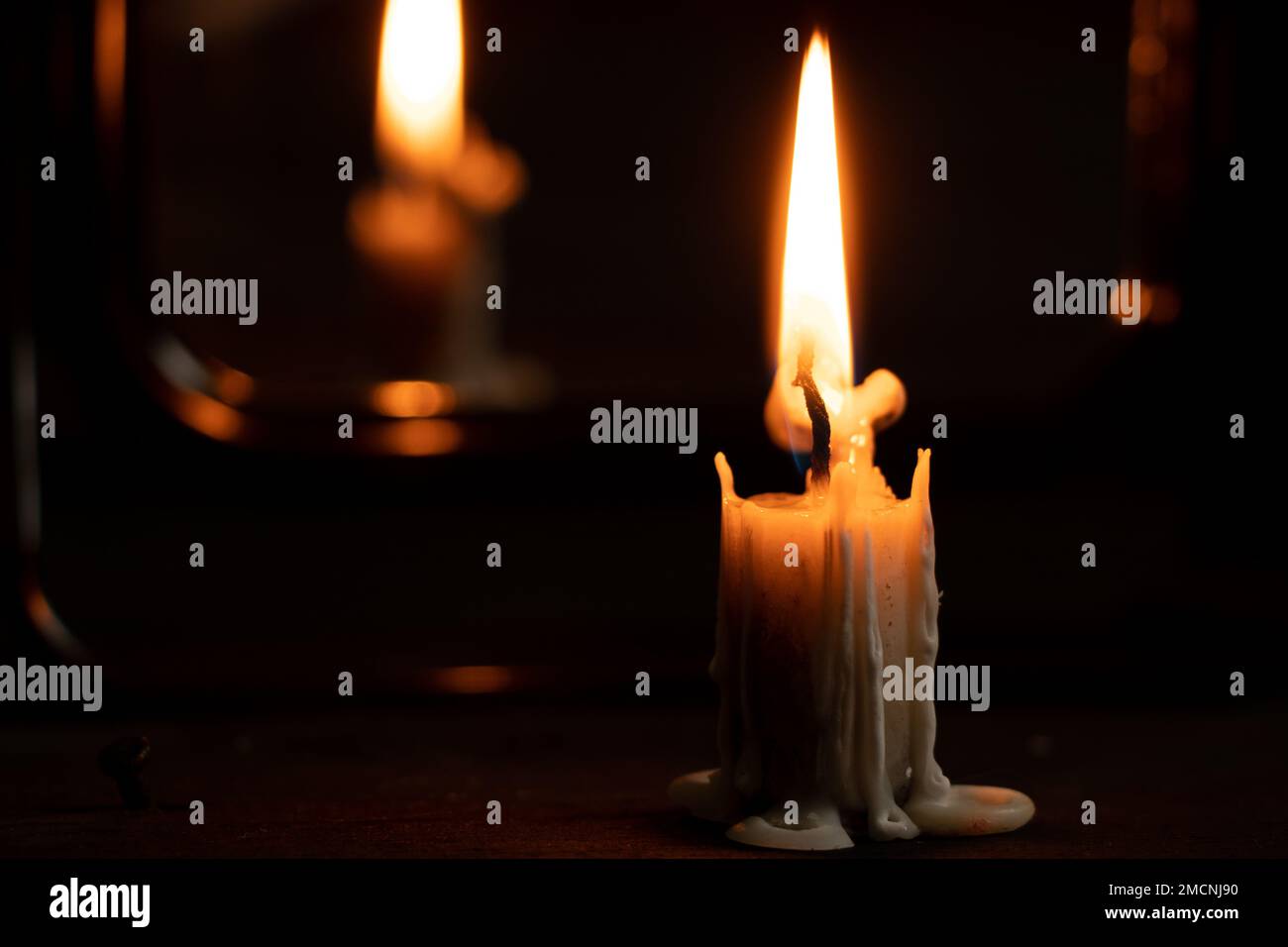 la vela ardiente se levanta sobre una mesa de madera negra en la oscuridad  cerca del espejo, el fuego de la vela en la oscuridad, la religión  Fotografía de stock - Alamy