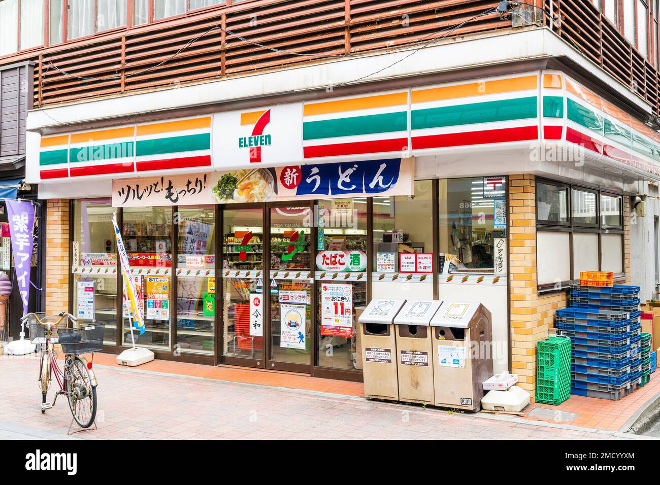 Japón Sugamo, Tokio. Comodidad Chain Store "7/11". Pequeña sucursal típica fachada de vidrio con entrada y papeleras de reciclaje fuera en la parte delantera. Foto de stock