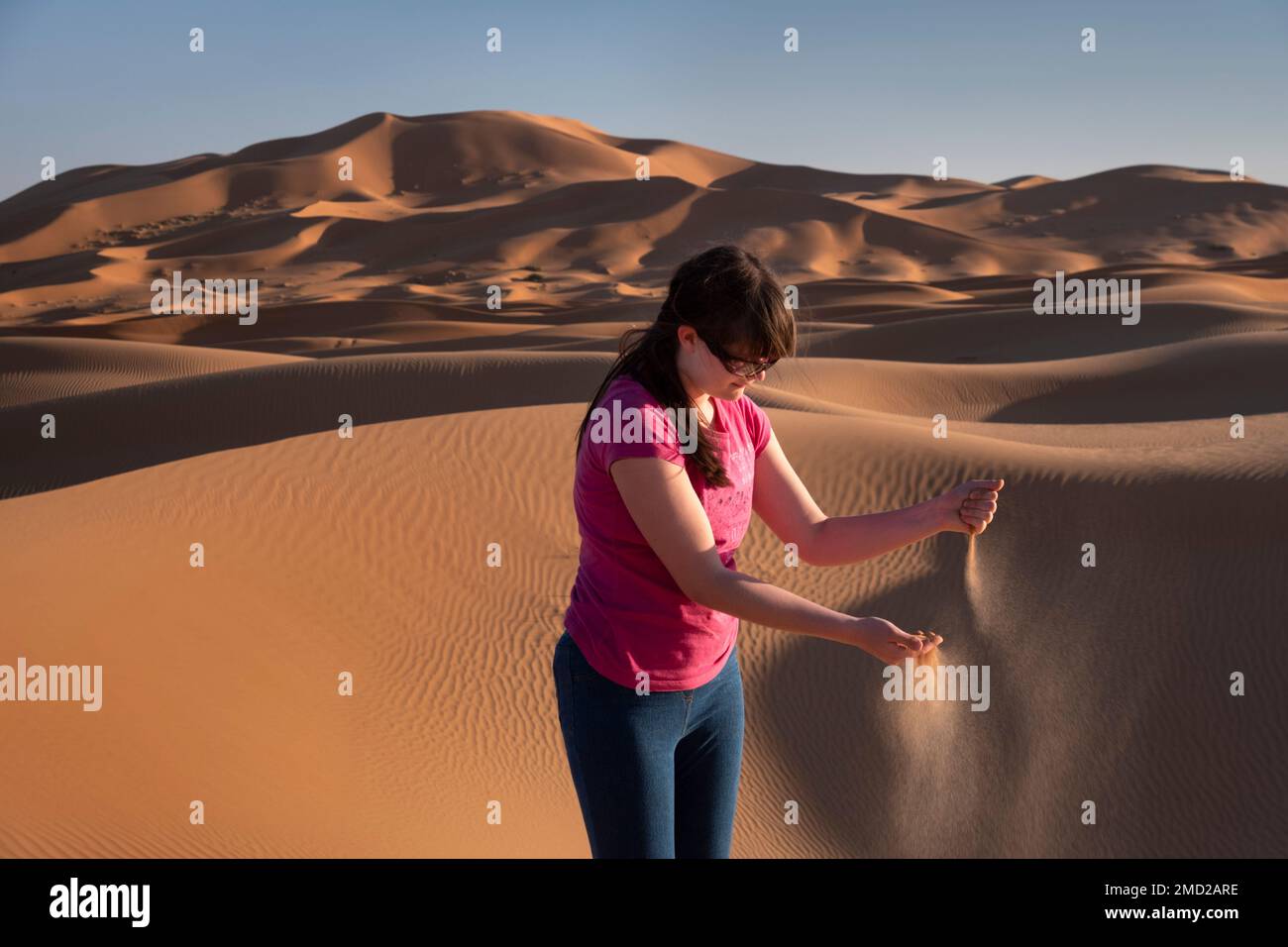 Adolescente jugando en las dunas de arena de Erg Chebbi, desierto del Sahara, Marruecos, África del Norte Foto de stock