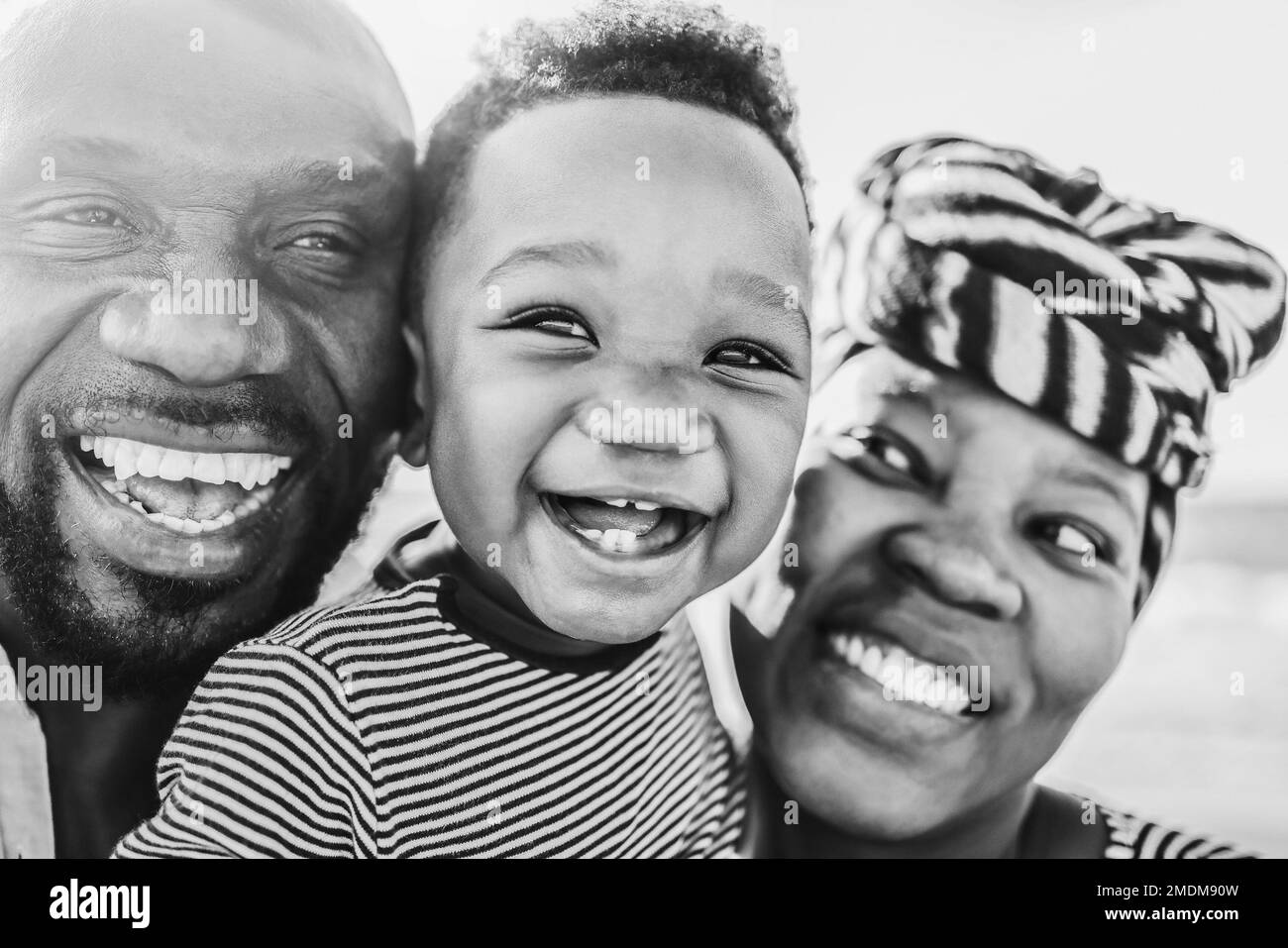 Familia africana divirtiéndose al aire libre - Enfoque principal en ojos de bebé - Edición en blanco y negro Foto de stock