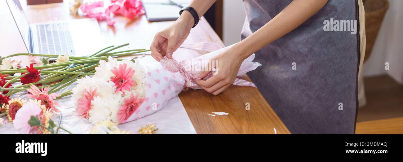 Concepto de floristería, floristería femenina que crea flores coloridas con papel y lazo de cinta. Foto de stock