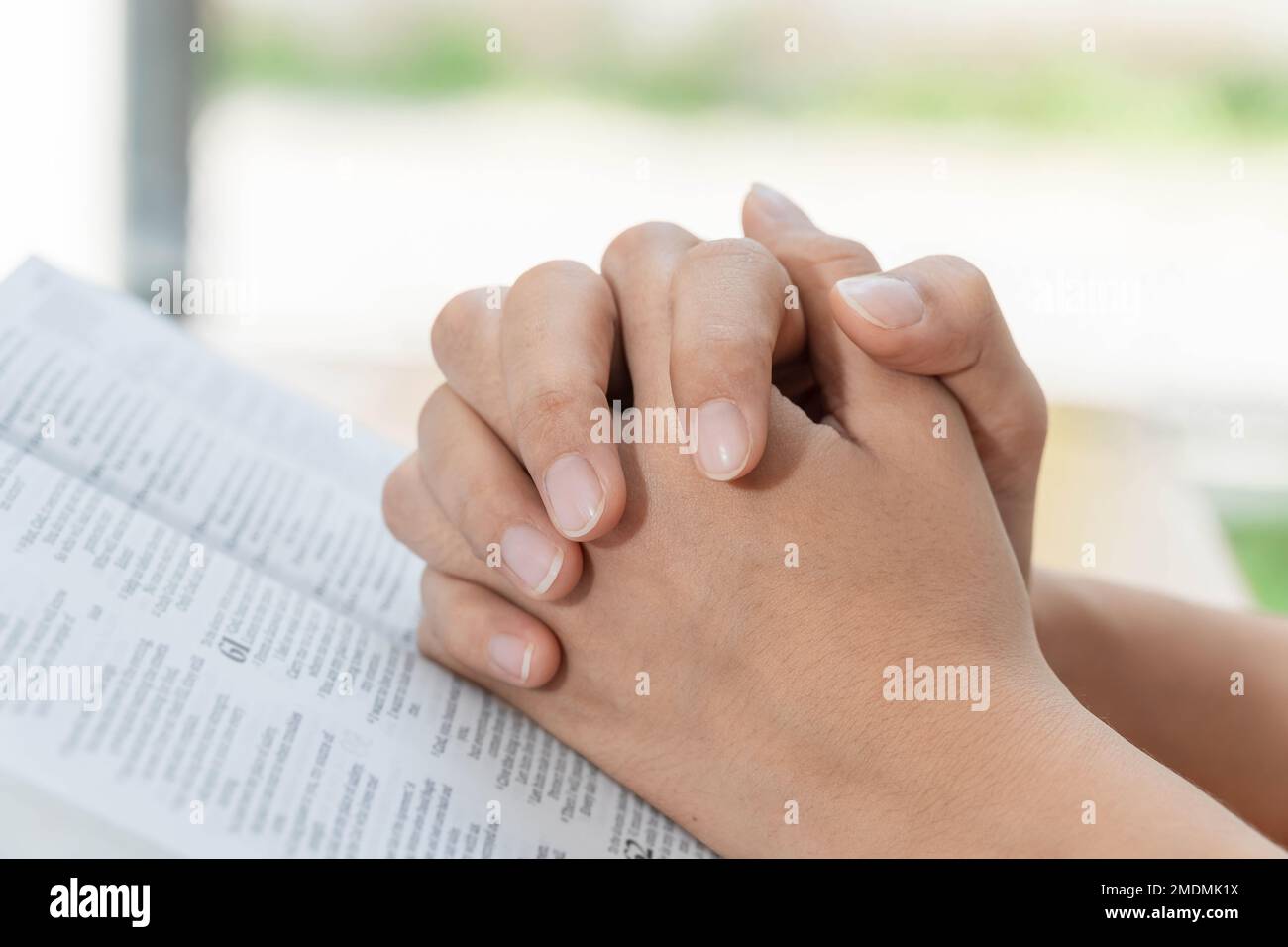 Rezar y el concepto de religión, las manos cristianas femeninas doblaron y leyeron la biblia a orar por la espiritualidad Foto de stock