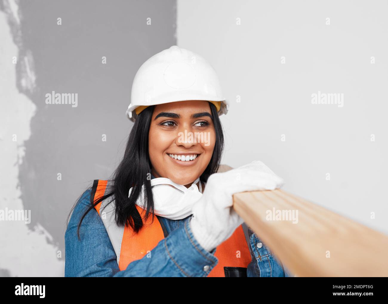 Una atractiva mujer del sur de Asia lleva tablones de madera lleva traje de construcción Foto de stock