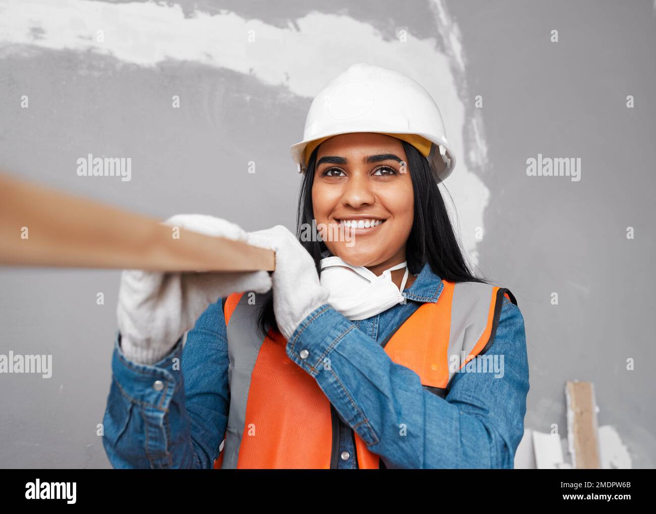 Una atractiva mujer del sur de Asia lleva tablón de madera con traje de construcción Foto de stock