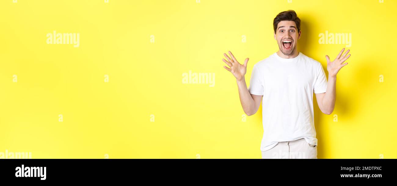 Retrato de un hombre emocionado y sorprendido reaccionando a una gran  oferta promocional, gritando por la alegría y triunfando, de pie sobre  fondo amarillo Fotografía de stock - Alamy