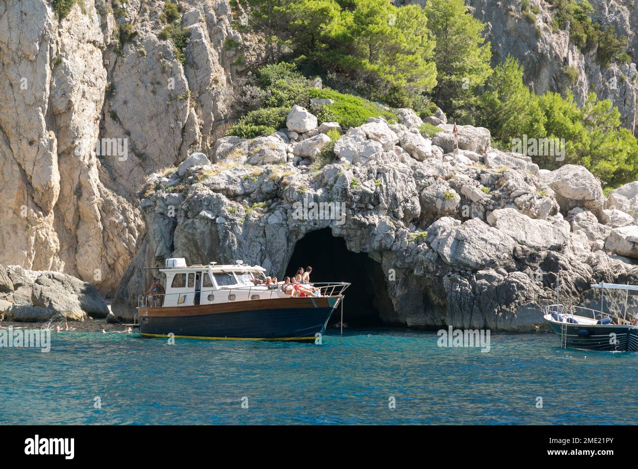 Gente en barco explorando las cuevas alrededor de la isla de Capri, en el mar Tirreno, Campania, Italia. Foto de stock