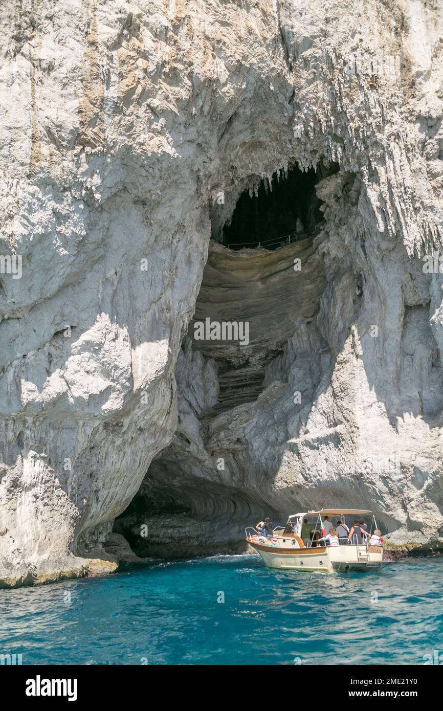 Gente en barcos explorando las cuevas alrededor de la isla de Capri, en el mar Tirreno, Campania, Italia. Foto de stock