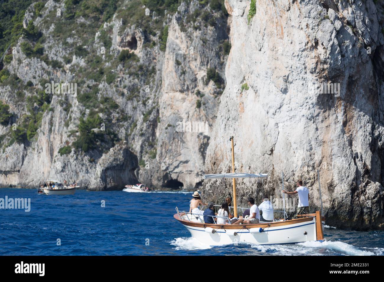 Gente en barcos explorando las cuevas alrededor de la isla de Capri, en el mar Tirreno, Campania, Italia. Foto de stock