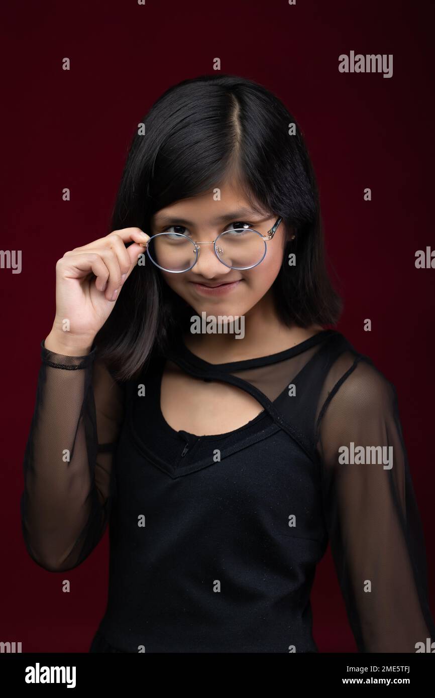 retrato de niña de 12 años aislado sobre fondo rojo con gla Foto de stock