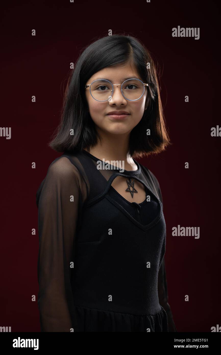 retrato de niña de 12 años aislado sobre fondo rojo con gafas Foto de stock