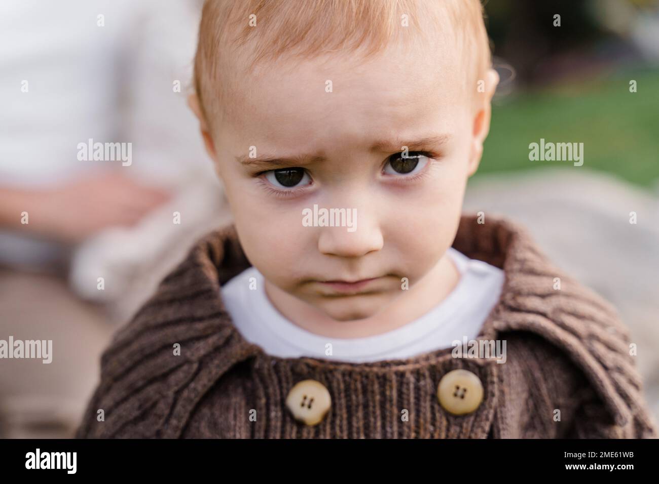 Un niño de ojos marrones caucásico bebé niño niño en un marrón tejido s Foto de stock