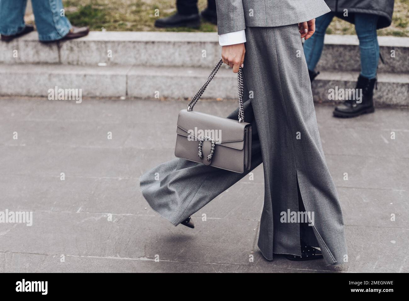 https://c8.alamy.com/compes/2megnwe/milan-italia-24-de-febrero-de-2022-mujer-en-chaqueta-gris-y-pantalones-de-pierna-ancha-con-monedero-de-cadena-2megnwe.jpg