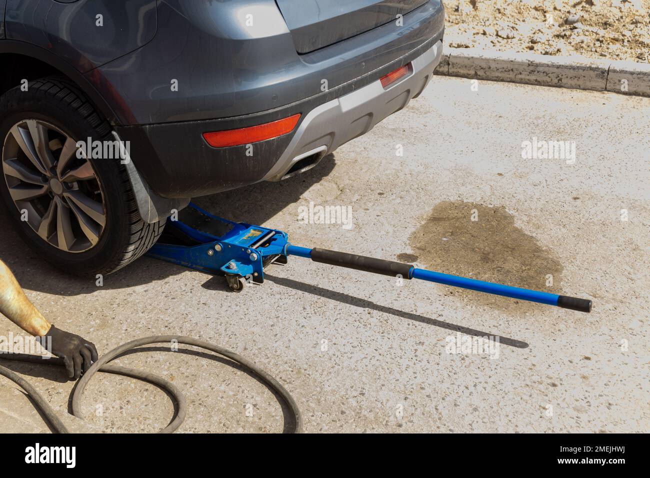 El gato hidráulico para coche levanta el coche nuevo para cambiar el neumático. Cambio de neumáticos estacional o concepto abstracto de servicio. Foto de stock