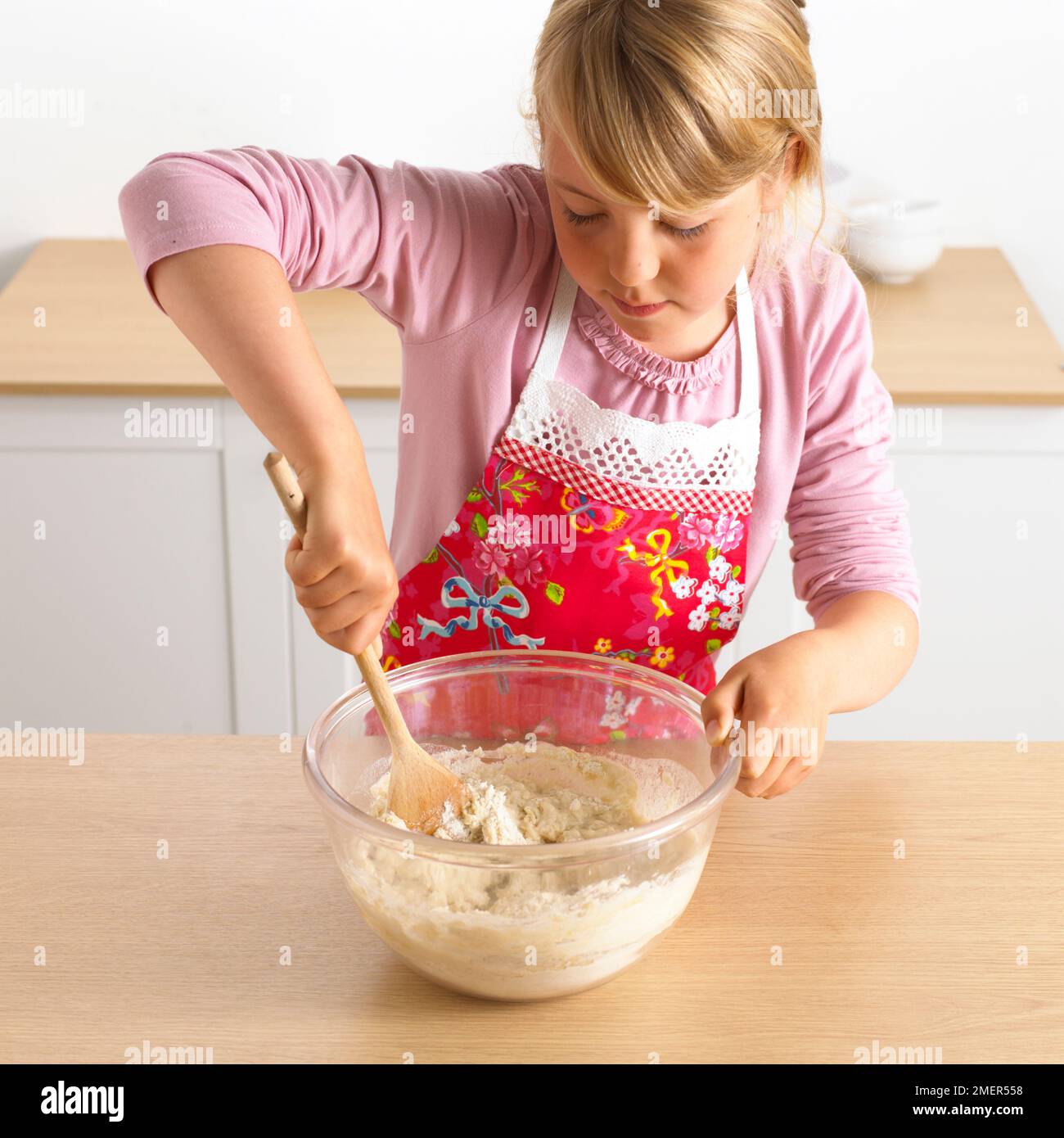 Chica mezclando un tazón de masa de pizza, 7 años Foto de stock