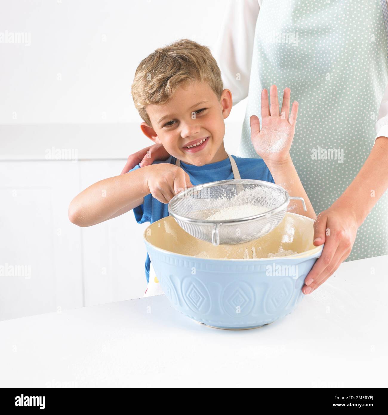 Niño tamizando la harina en un tazón de mezcla, 6 años Foto de stock