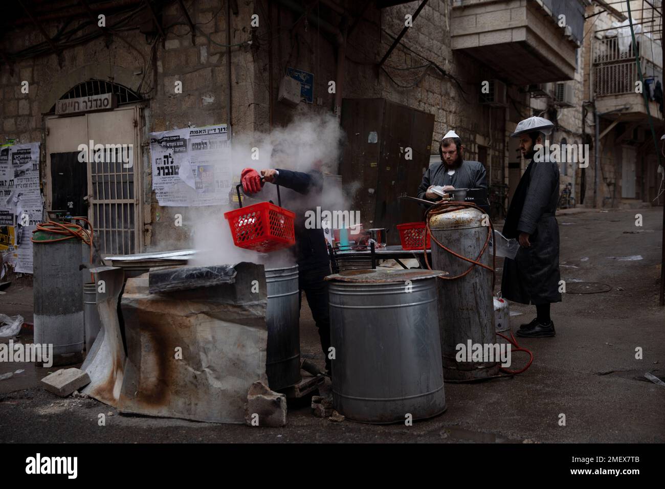 An ultraOrthodox Jewish man dips cooking utensils in boiling water to
