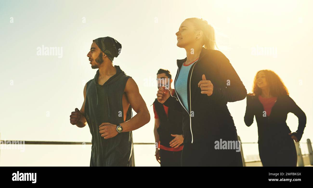 Los amigos proporcionan un impulso extra de motivación. un grupo de fitness corriendo en el paseo marítimo. Foto de stock