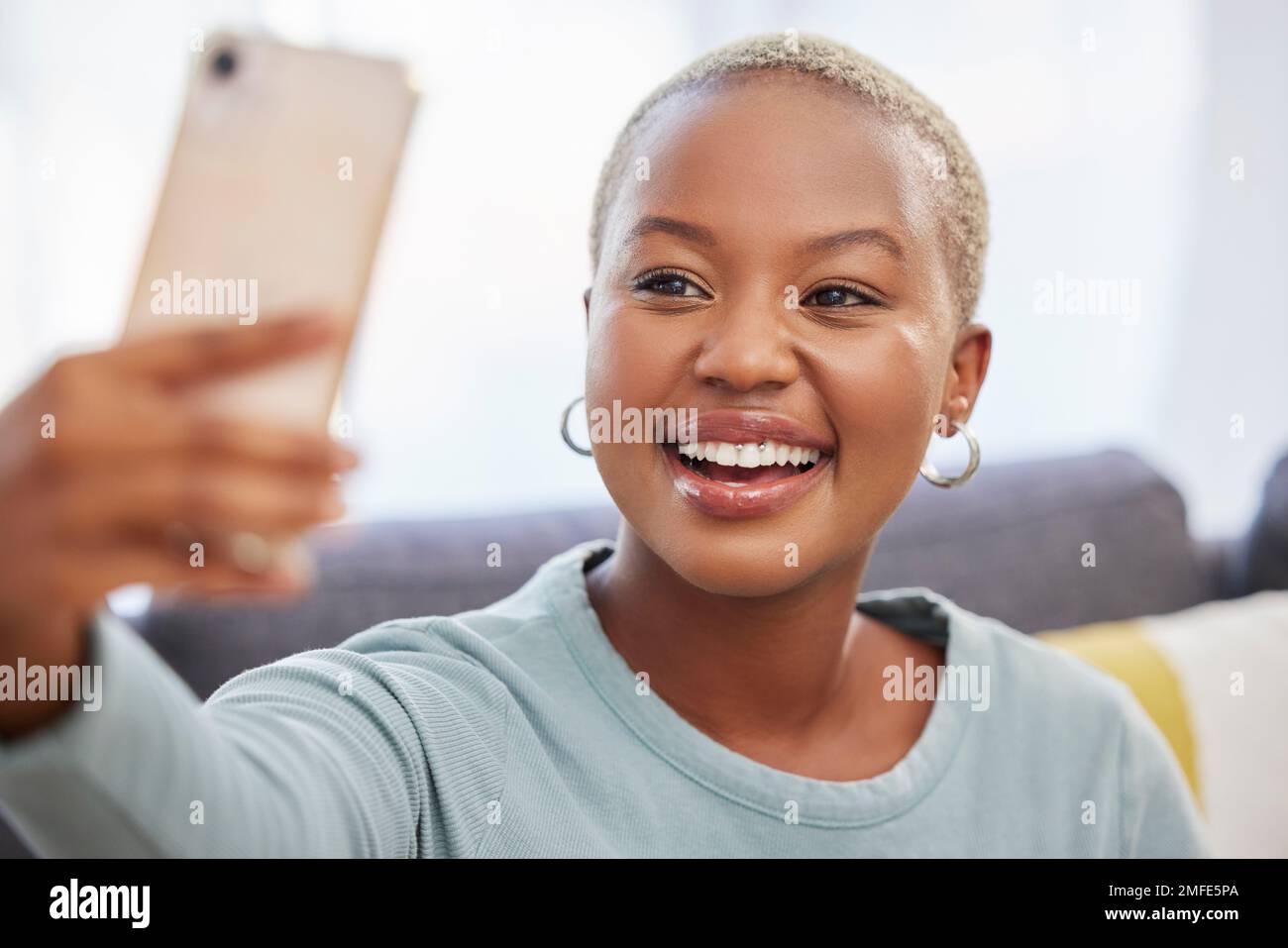 Mujer negra, influencer y sonrisa para selfie, redes sociales o foto de perfil que se relaja en el sofá de la sala de estar en casa. Vlogger femenino afroamericano Foto de stock