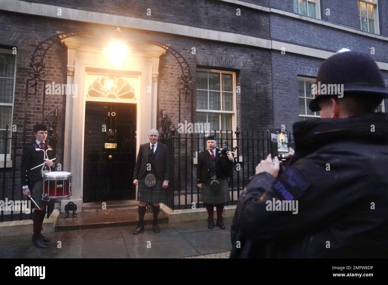 Un policía tomando una foto de un invitado fuera del 10 Downing Street antes de una recepción de Burns Night organizada por el primer ministro Rishi Sunak. Fecha de la fotografía: Miércoles 25 de enero de 2023. Foto de stock