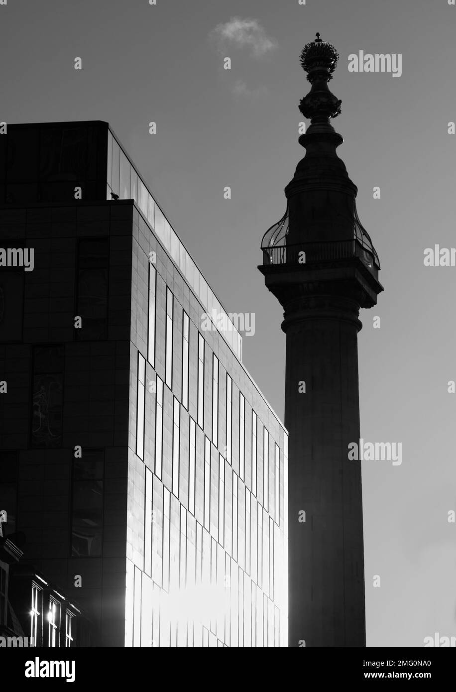 Monocromo, blanco y negro del monumento en silueta retroiluminado por el sol contrastó con Un moderno bloque de oficinas, la ciudad de Londres, Reino Unido Foto de stock