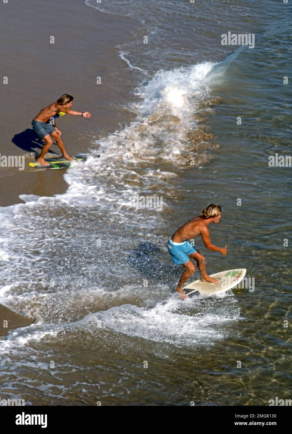 Hombres jóvenes skim boarding en la costa del sur de California, EE.UU. Foto de stock
