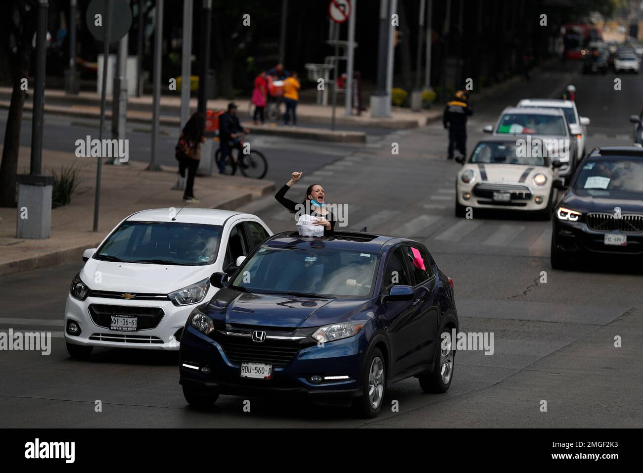 A woman chants from a car sunroof as hundreds of cars participate in a